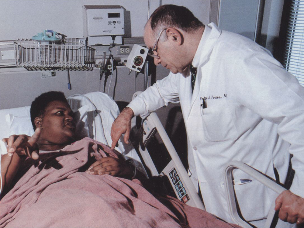 A doctor leaning over a patient in a hospital bed.