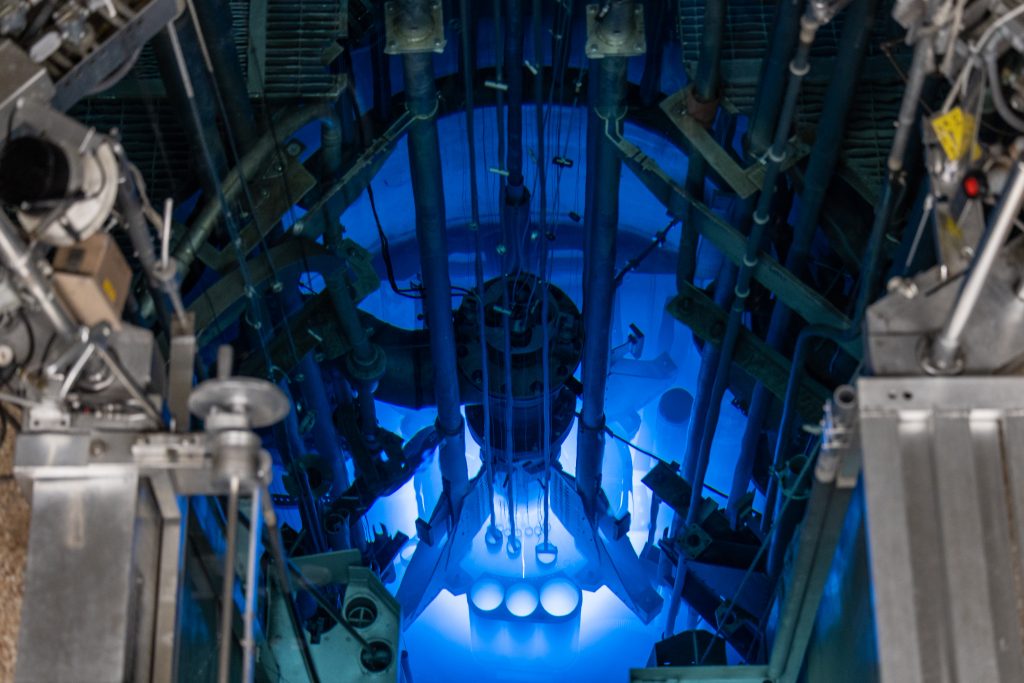 A nuclear reactor glowing blue in a dark room.